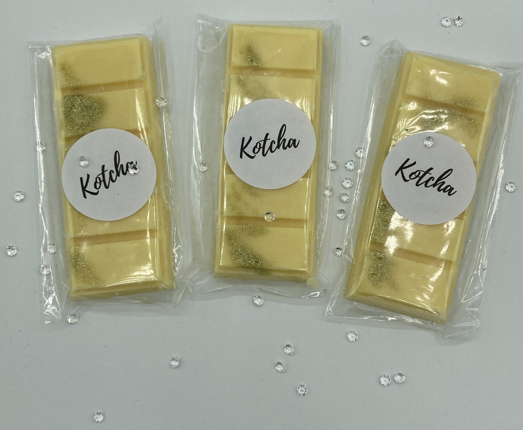 The picture is of a wax melt in the shape of a chocolate bar. The colour is yellow with gold biodegradable glitter wrapped in plastic with the brand name 